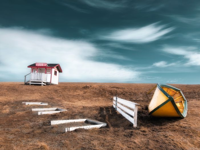 A fine-art photo shows a beached boat and a white shack with a red roof.